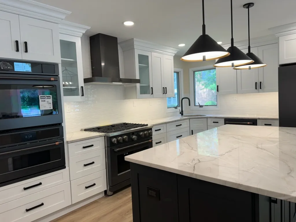 Dark island with a light stone top and black appliances