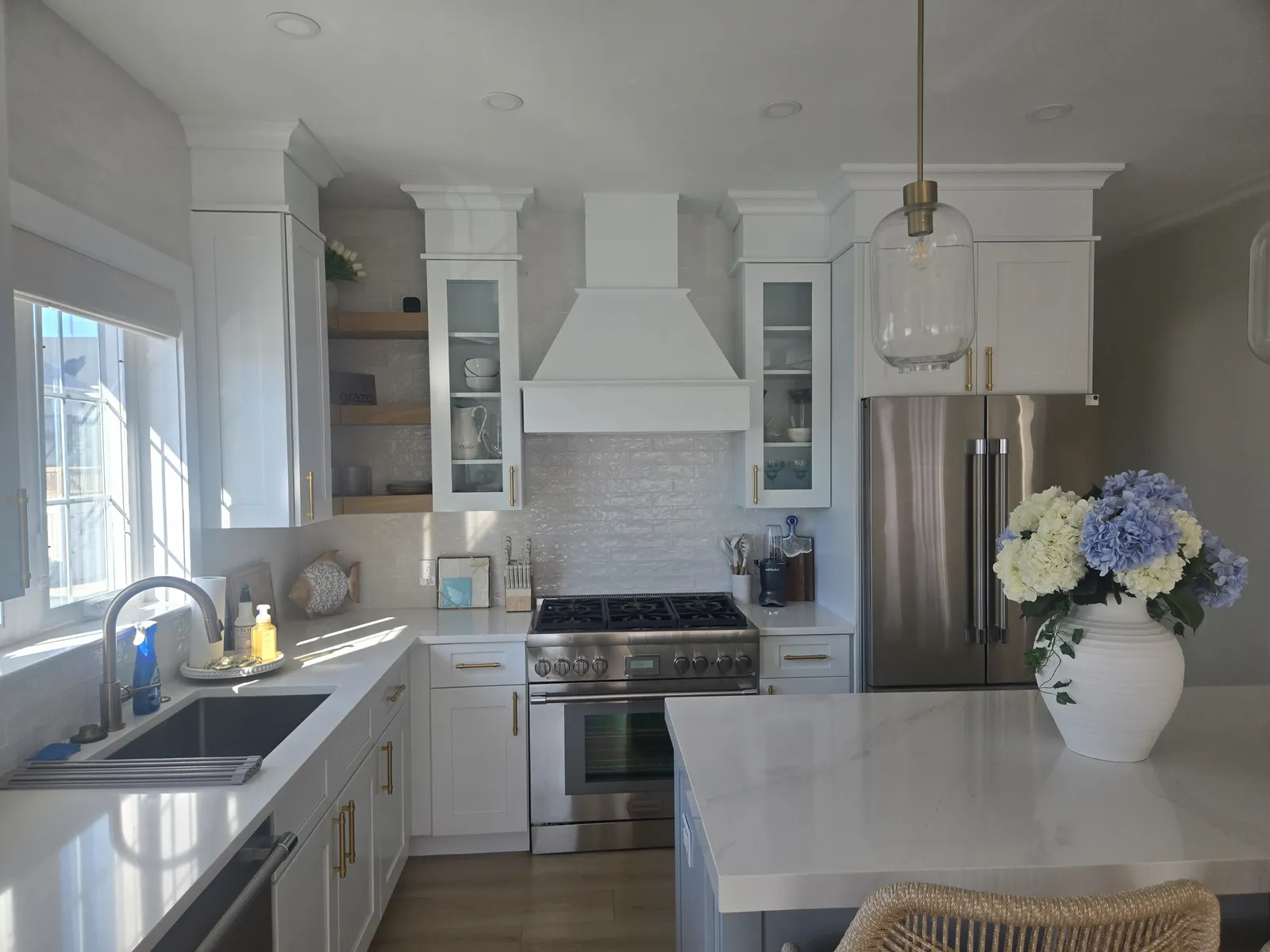 White stone counters and a farmhouse sink in a bright kitchen