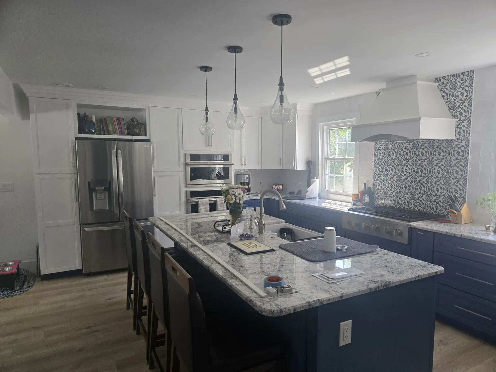 Granite island top on navy cabinets with the fridge wall beyond