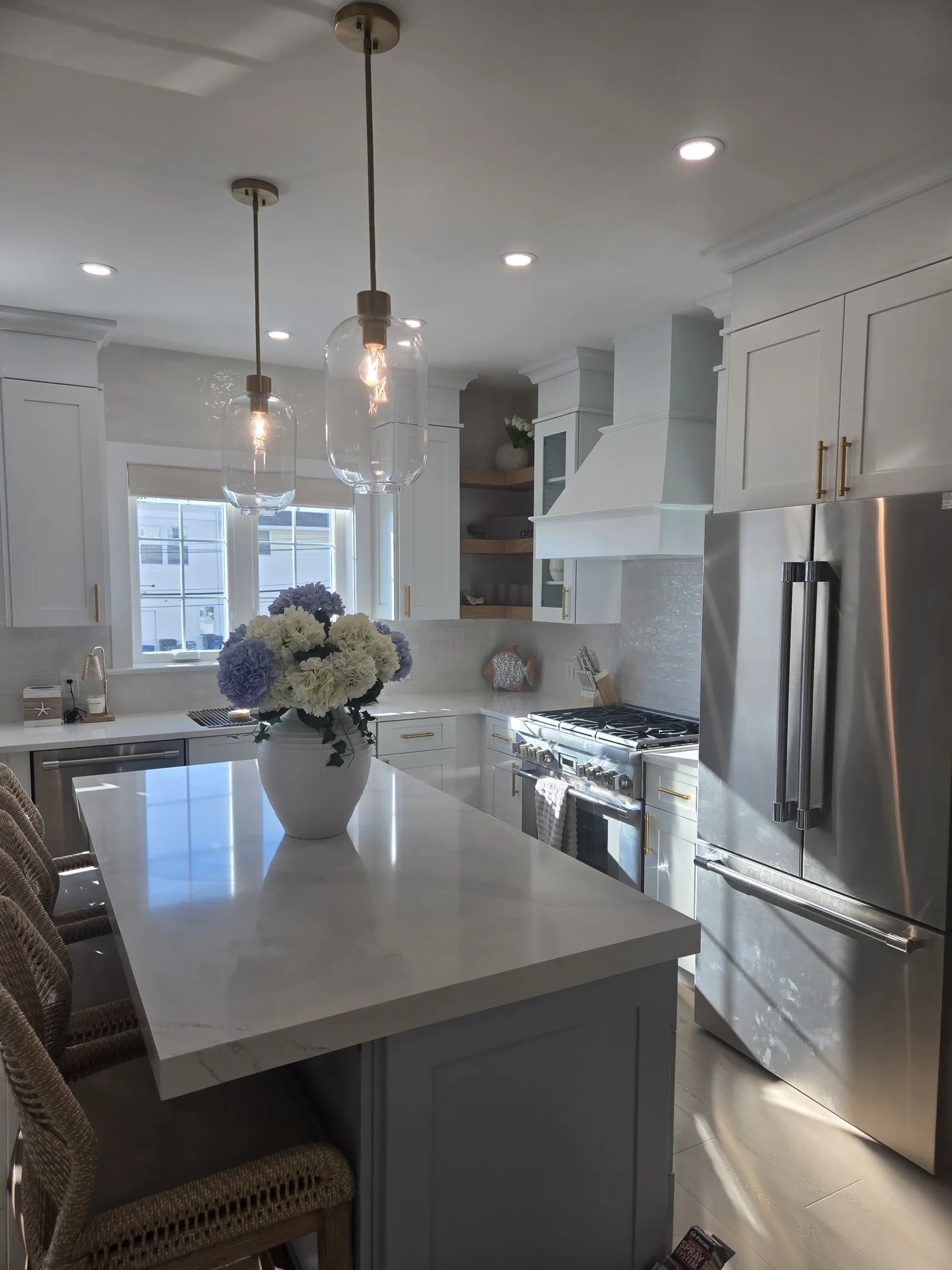 White kitchen with a stone island and a plaster range hood